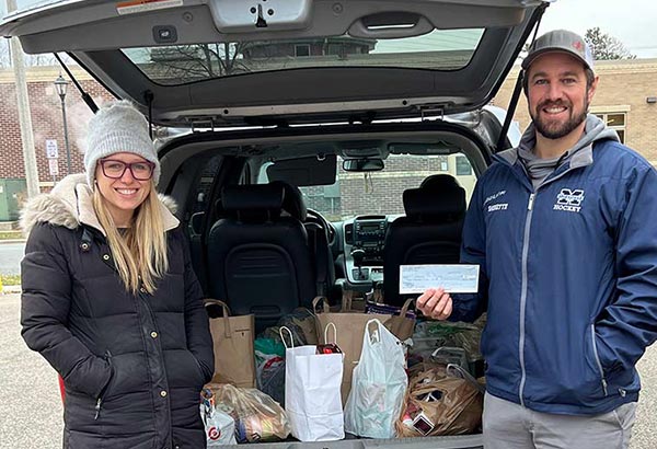 A young couple stand next to their car full of food donations for the McFarland Food Pantry